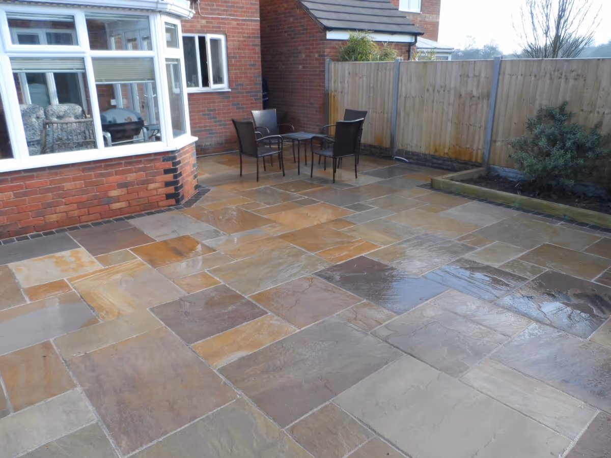 Mixed size camal natural stone patio with large charcoal rumbled block and sleeper planter