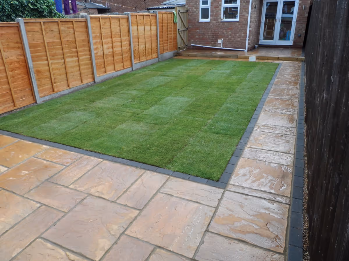 Two size autumn gold concrete patio with standard charcoal block, sleeper step, new lawn and treated lap fence panels with concrete posts and gravel boards. 