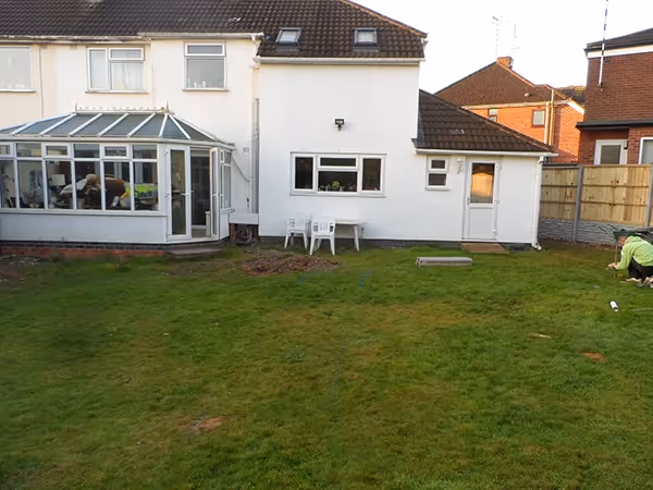 Mixed size camal natural stone patio with large charcoal rumbled block, sleeper retaining beds and new lawn. 