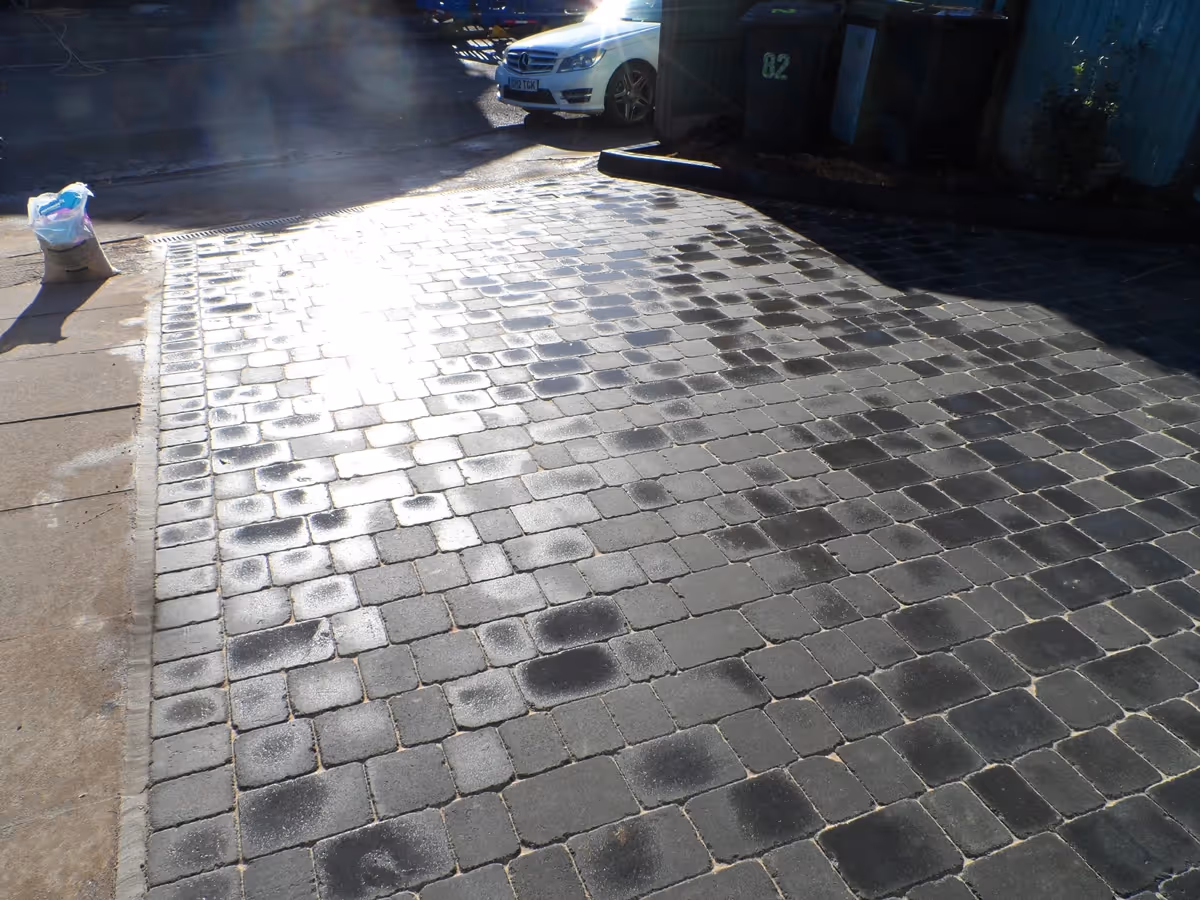 Charcoal Rumbled paving set driveway with K.L kerb planter and an ACO channel drainage system - angle 2
