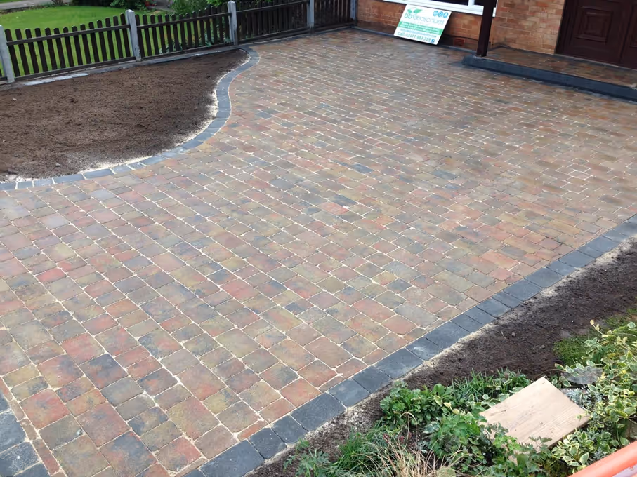 Autumn mix Rumbled paving set driveway with single charcoal border, K.L kerb platform step and large planter area - angle 3