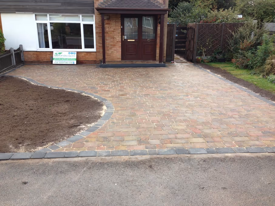 Autumn mix Rumbled paving set driveway with single charcoal border, K.L kerb platform step and large planter area - angle 2
