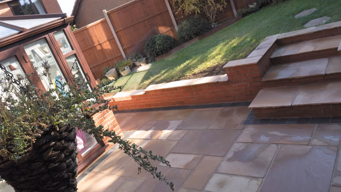 Mixed size camal natural stone patio with three size charcoal rumbled block, red brick wall and steps finished with camal copings