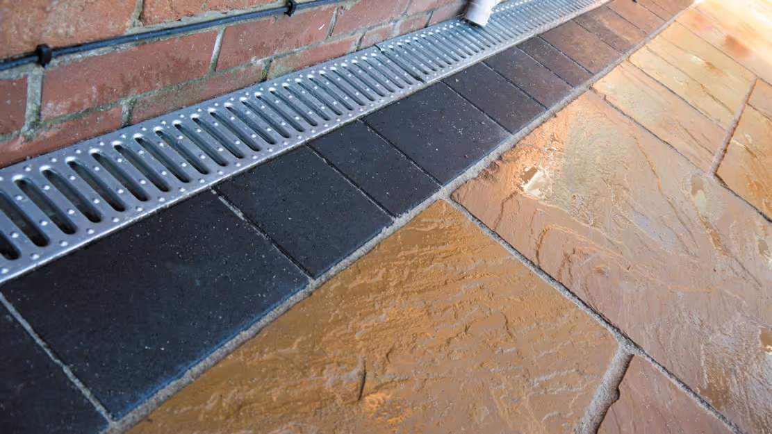 Mixed size camal natural stone patio with three size charcoal rumbled block, red brick wall and steps finished with camal copings - angle 2