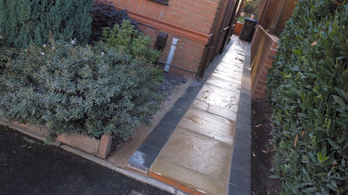 Mixed size camal natural stone patio with three size charcoal rumbled block, red brick wall and steps finished with camal copings - angle 3