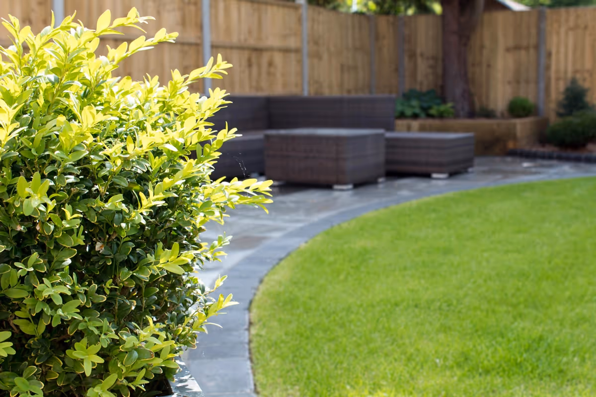 Mixed size grey natural size patio with large charcoal rumbled block, sleeper planter area and small kerb edging - angle 4