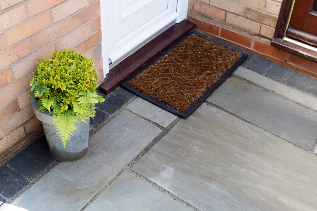 Mixed size grey natural size patio with large charcoal rumbled block, sleeper planter area and small kerb edging - angle 6