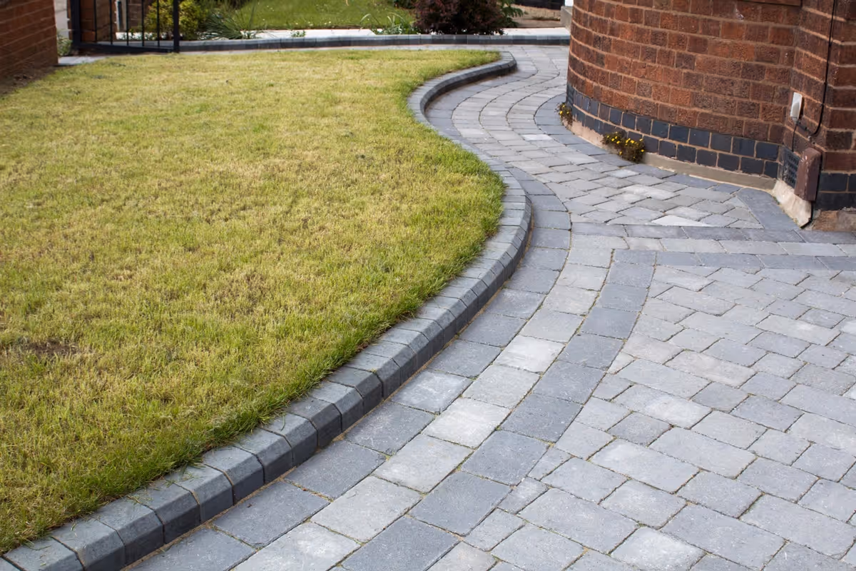 Ash Rumbled paving set driveway with triple border in charcoal, new lawn area retained with K.S kerb sets - angle 2