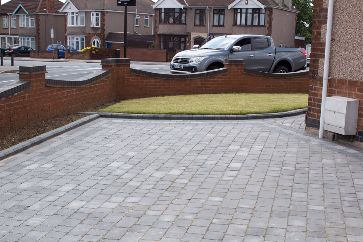 Ash Rumbled paving set driveway with triple border in charcoal, new lawn area retained with K.S kerb sets - angle 1