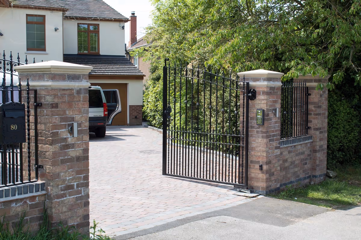 Brindle Rumbled paving set driveway with rustic brick wall and pillars.