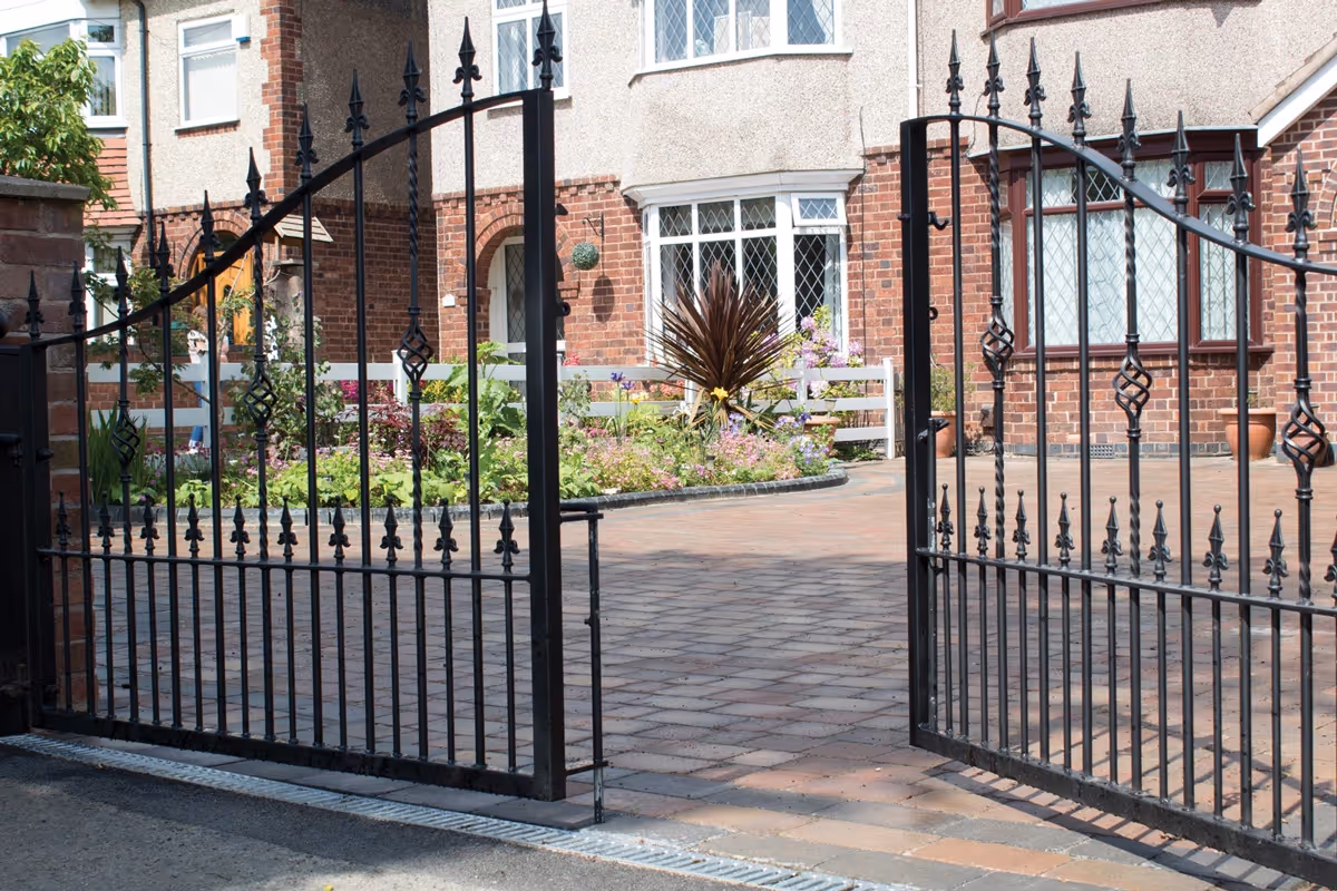 Autumn mix Rumbled paving set driveway with triple border in charcoal, raised planter using K.S kerb sets, ACO channel drainage system installed and new iron gates
