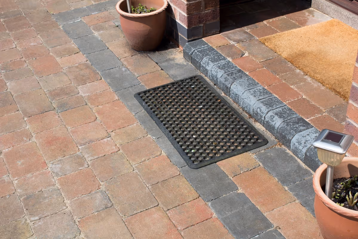 Autumn mix Rumbled paving set driveway with triple border in charcoal, raised planter using K.S kerb sets, ACO channel drainage system installed and new iron gates - angle 3