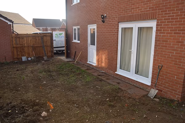 Mixed size grey sandstone with a large charcoal rumbled block, sleeper step and new lawn. 
