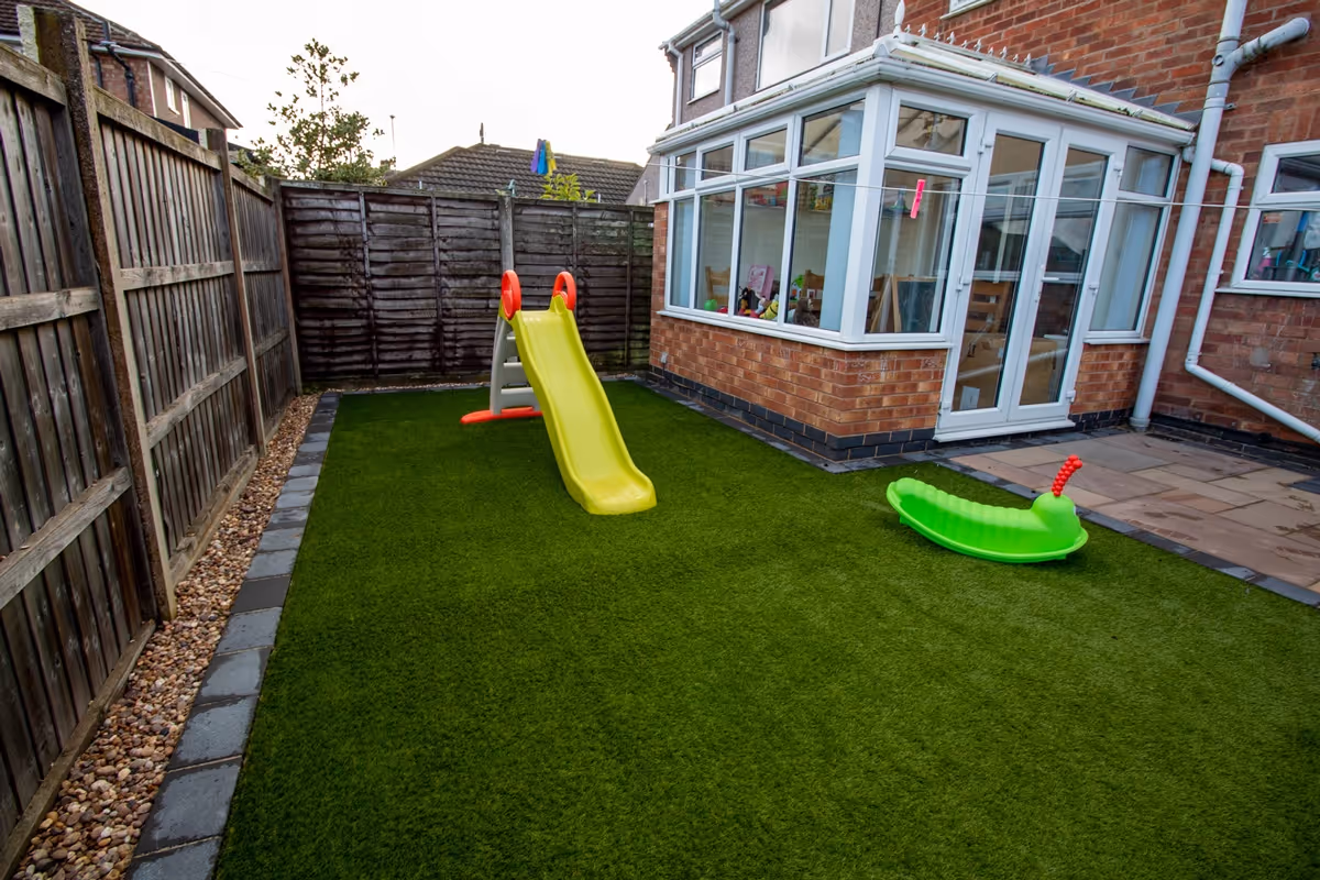 Artificial grass with large charcoal rumbled block border. 