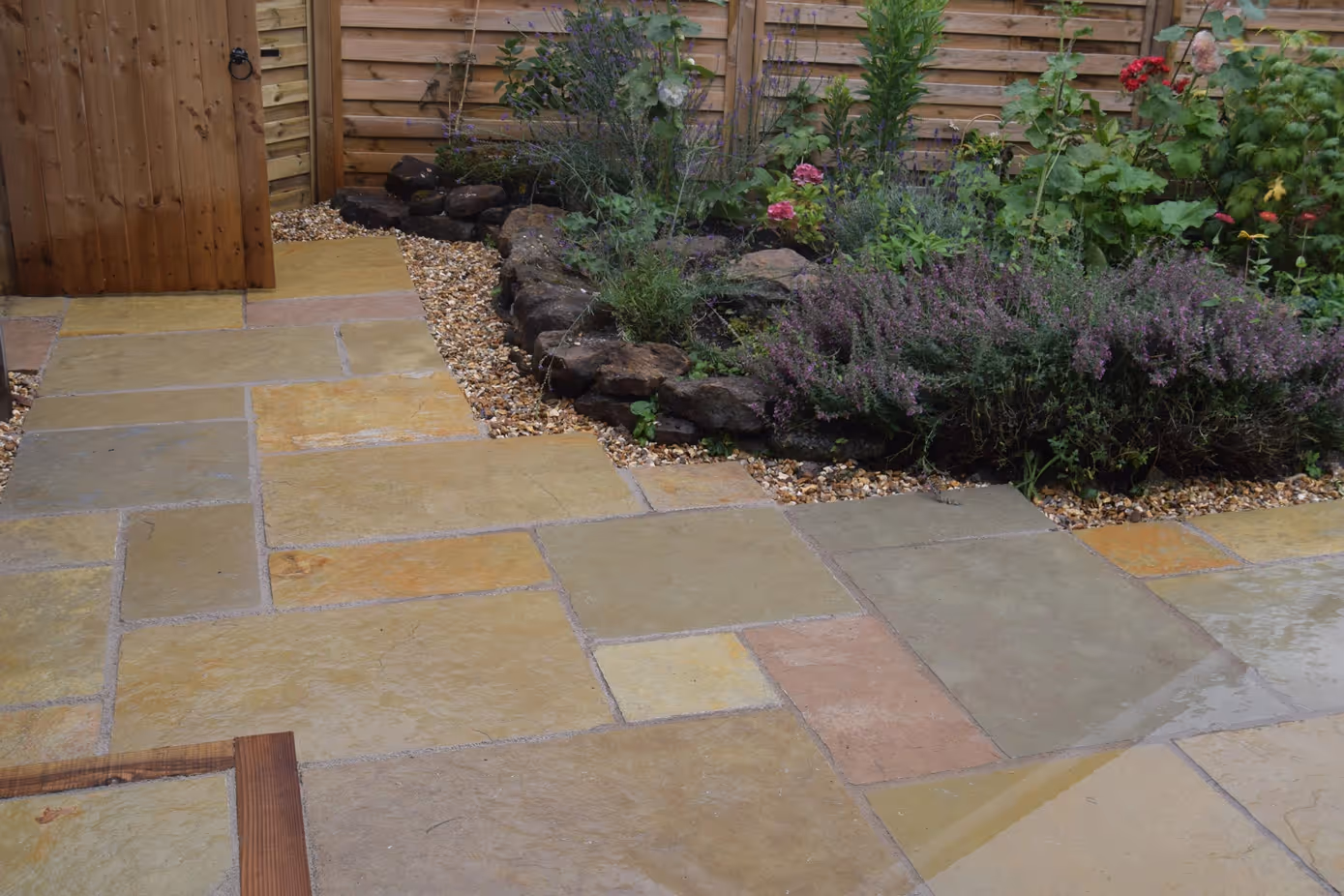Yellow Limestone, mix size slabs with recessed man-hole tray. Treated timber step and timber sleepers to retain patio. Golden decorative chipping stones.