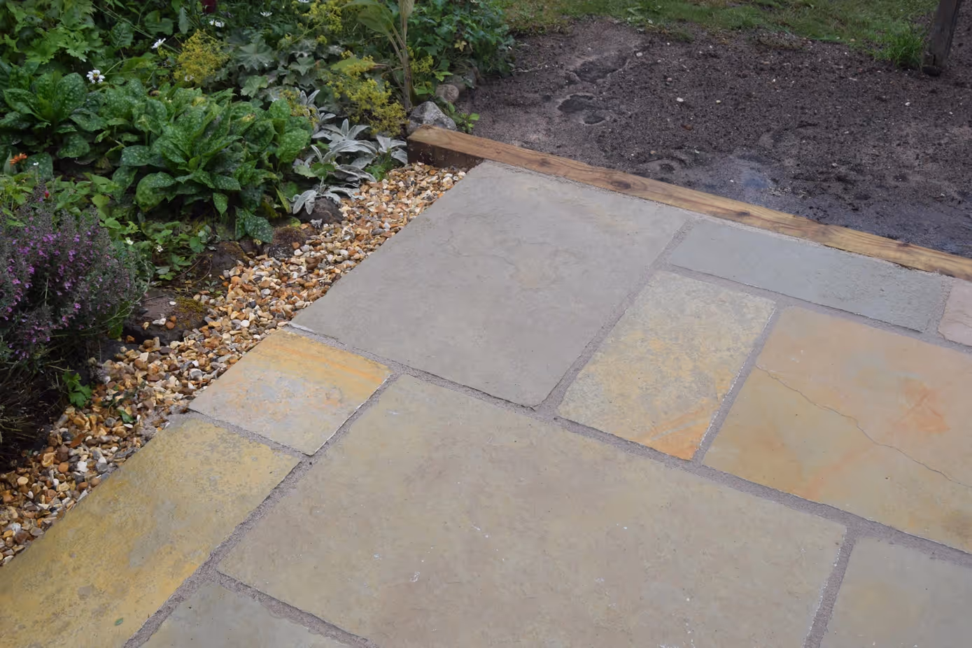 Yellow Limestone, mix size slabs with recessed man-hole tray. Treated timber step and timber sleepers to retain patio. Golden decorative chipping stones. - angle 3