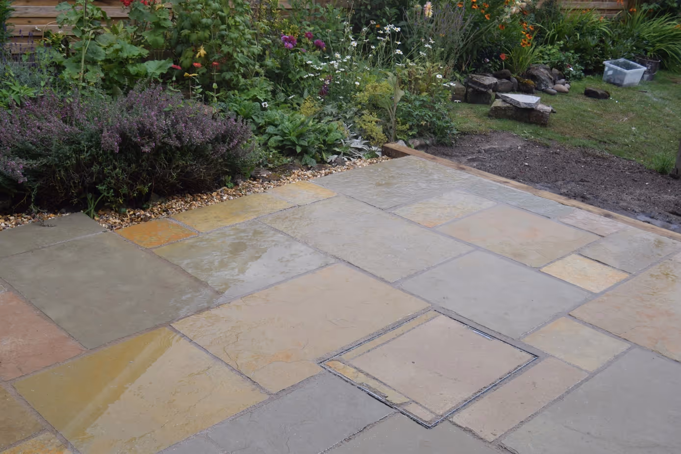 Yellow Limestone, mix size slabs with recessed man-hole tray. Treated timber step and timber sleepers to retain patio. Golden decorative chipping stones. - angle 2