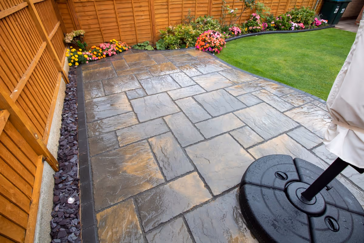 Rutland Winter Stone, 3 size paving with a Granite Resin based jointing compound. A standard Charcoal Paver around perimeters. A small Charcoal Kerb Set to retain planters. Plumb Slate decorative stones. - angle 4