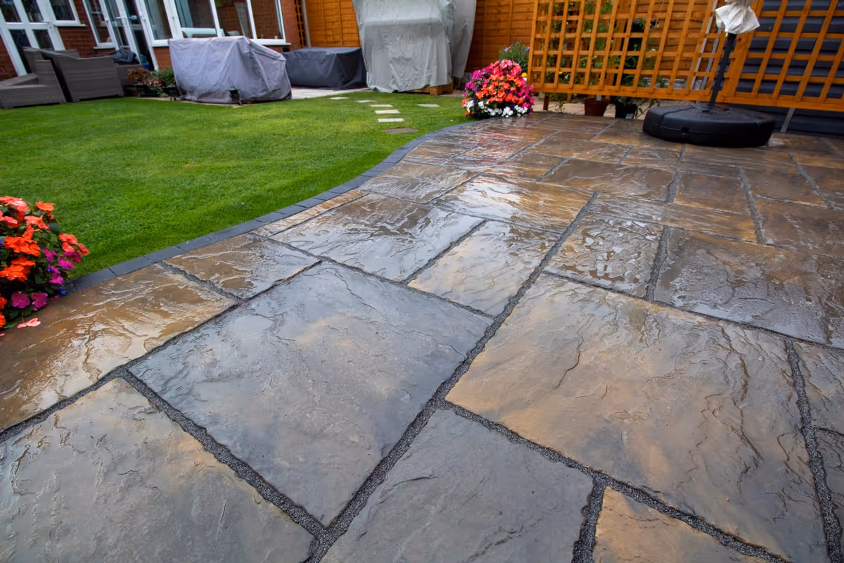 Rutland Winter Stone, 3 size paving with a Granite Resin based jointing compound. A standard Charcoal Paver around perimeters. A small Charcoal Kerb Set to retain planters. Plumb Slate decorative stones. - angle 8