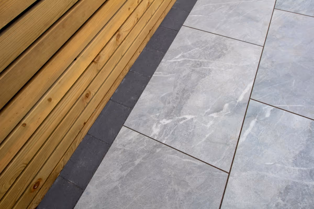 Raised-toped Total Stone Grigio porcelain slabs with Charcoal curb set. Venetian-style screening with downlights. Sleeper beds. Charcoal pencil edge paving border - angle 2