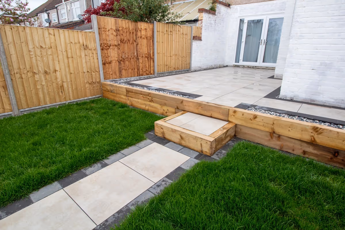Town soft grey square porcelain slabs with charcoal pencil edge paving. Black Ice gravel. Sleeper retainers. Fence with concrete posts and gravel boards.