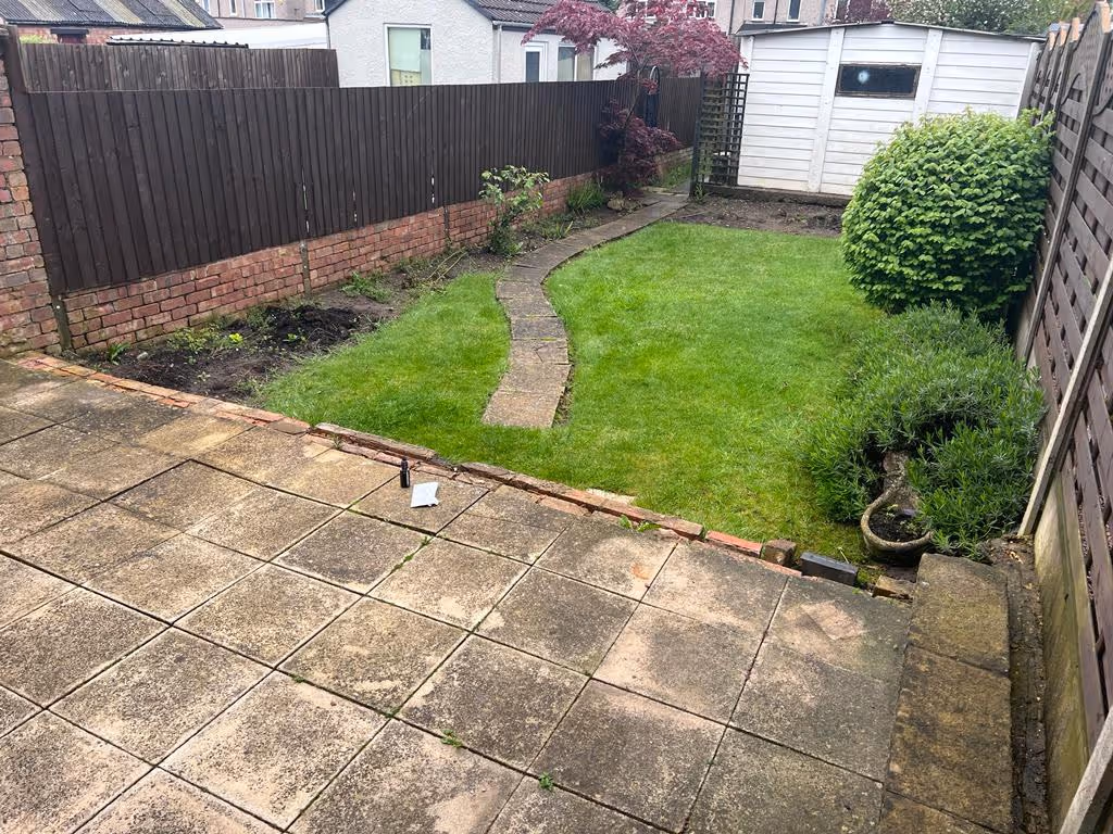 Total Stone mixed-size porcelain patio with charcoal pencil edge paving. Pet-friendly artificial turf. Cotswold decorative chipping. Sleeper retainers. Venetian screening.