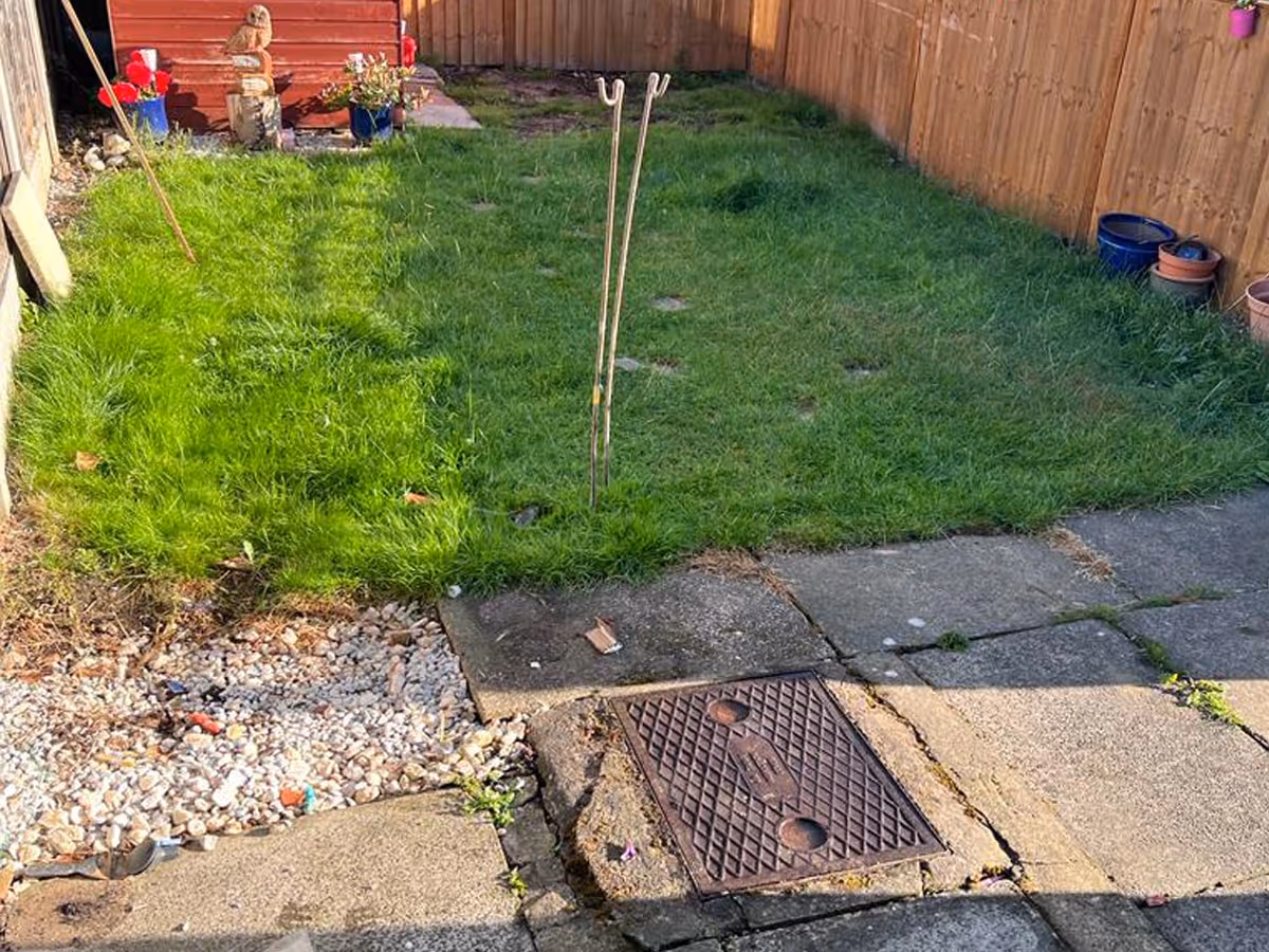 Kandla grey mixed-size porcelain patio with charcoal pencil edge paving. Inset manhole tray. ACO drainage system. Pet-friendly artificial lawn