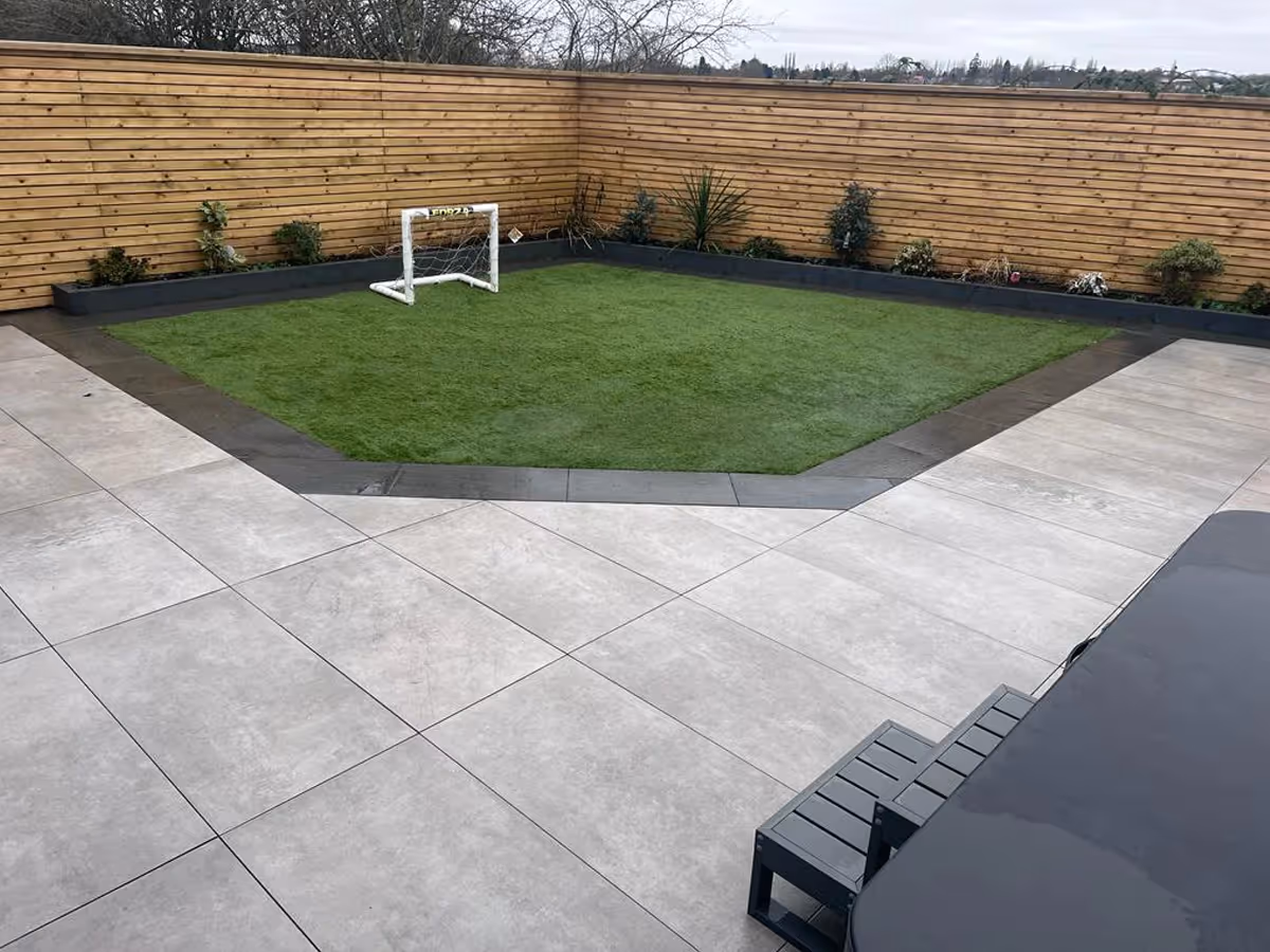 Evoque Greige porcelain Slabs with Grinito Anthracite edges. Sleeper beds. Artificial lawn. Venetian fencing with led strip light.