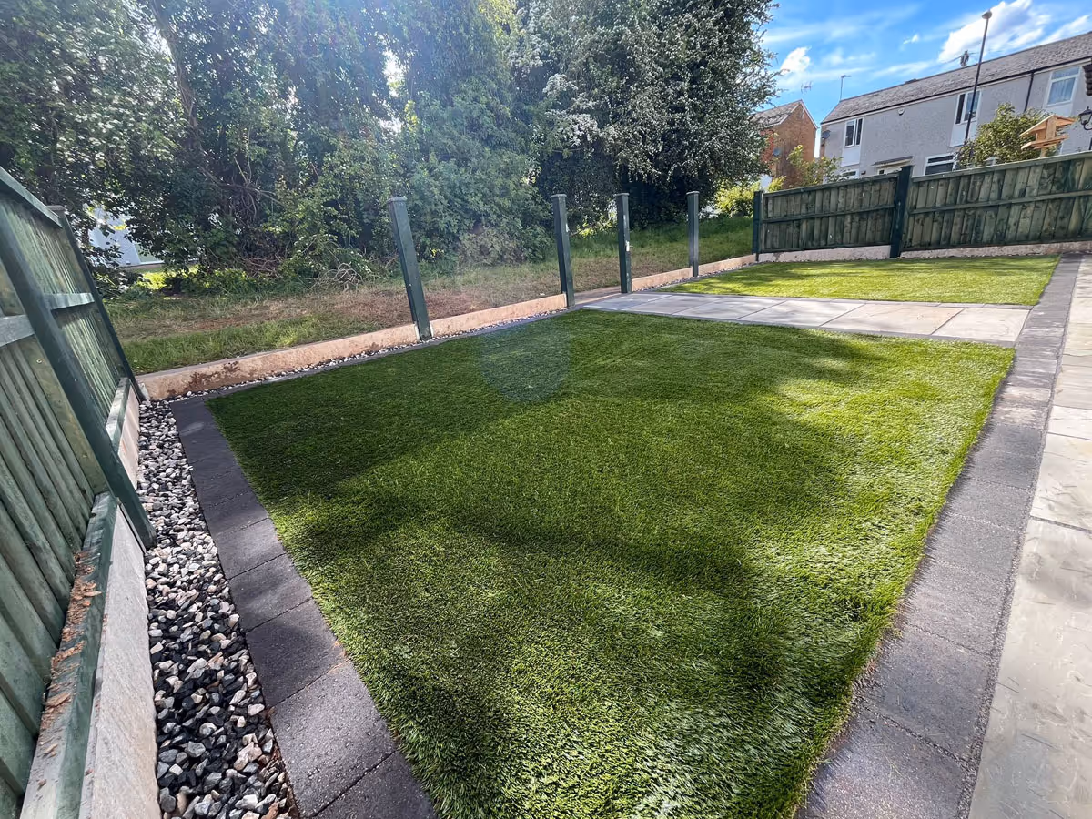 Natural stone patio with charcoal pencil edge paving and artificial lawn - angle 1