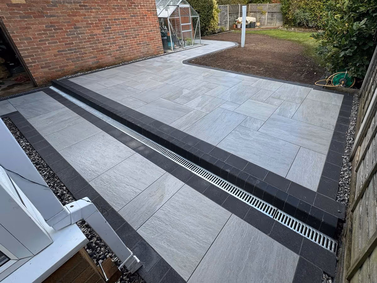 Total Stone Grigio porcelain patio with charcoal pencil edge paving and ACO drain - angle 1