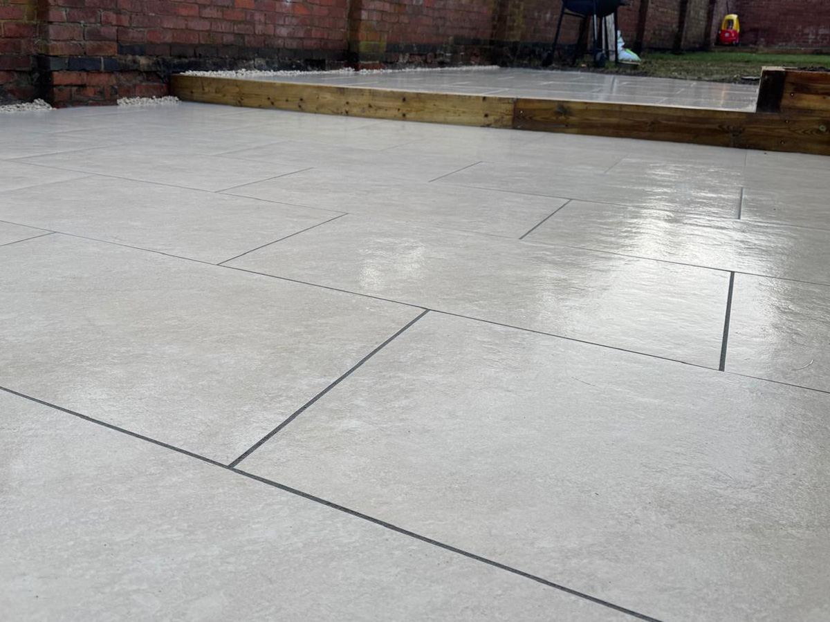 Grey porcelain patio with sleeper retainers and decorative chipping - angle 2