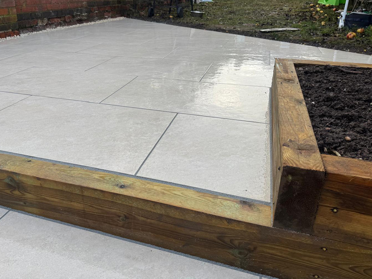 Grey porcelain patio with sleeper retainers and decorative chipping - angle 5
