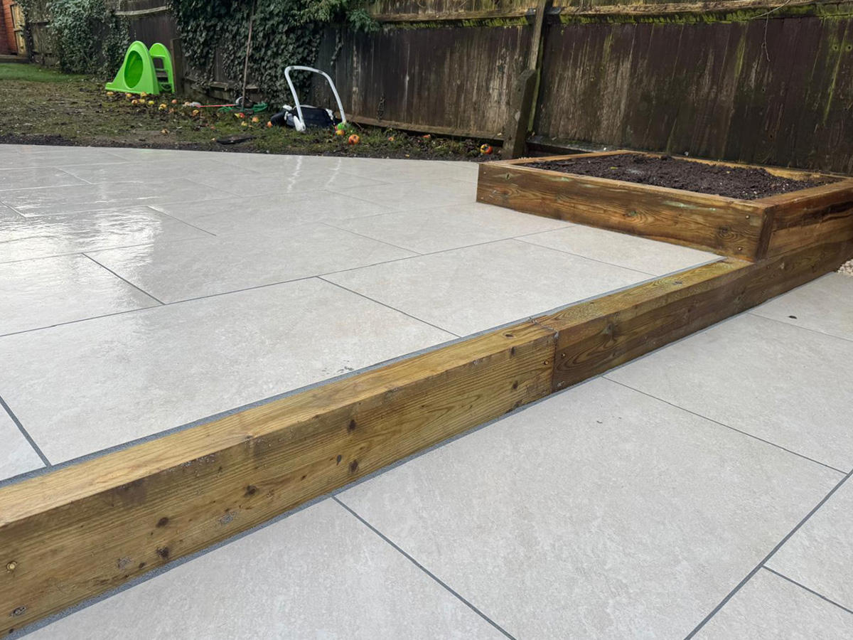 Grey porcelain patio with sleeper retainers and decorative chipping - angle 1