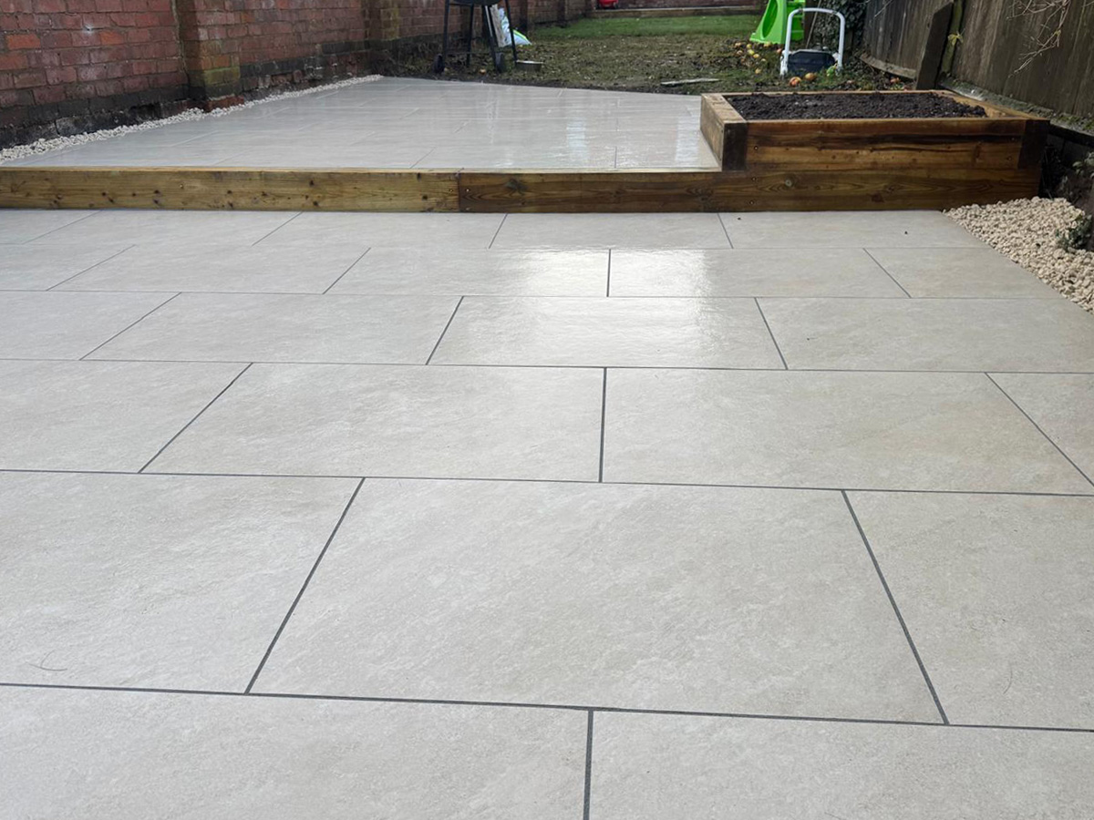 Grey porcelain patio with sleeper retainers and decorative chipping - angle 3