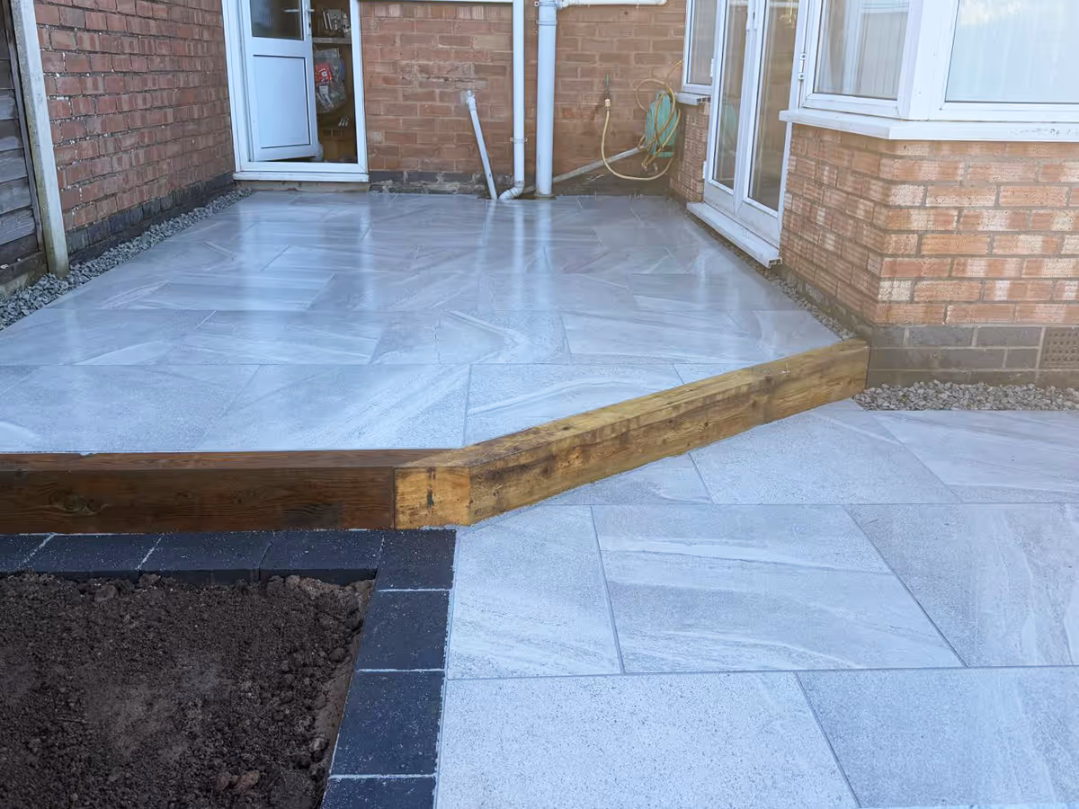 Grey porcelain patio with sleepers pencil edge paving.