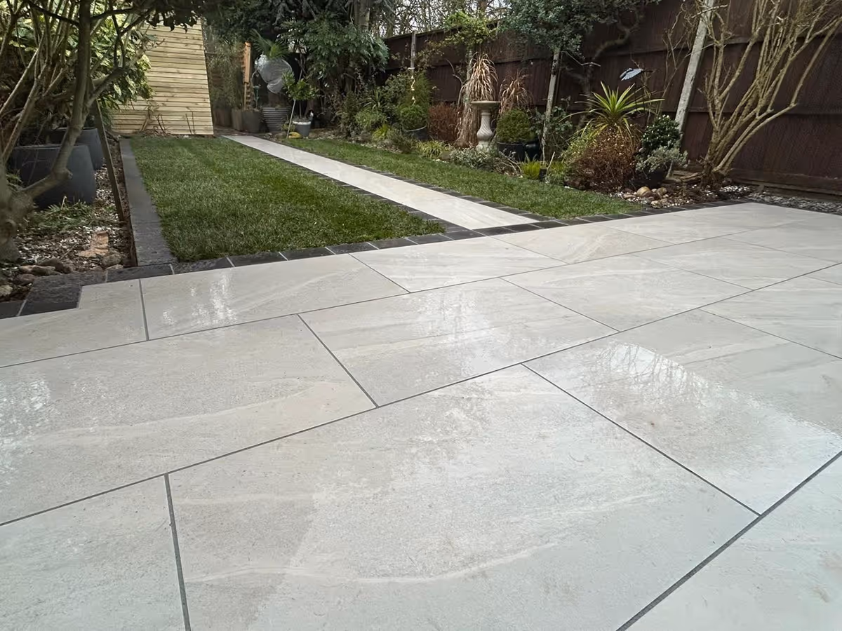 Grey porcelain patio with charcoal pencil edge paving and artificial turf.