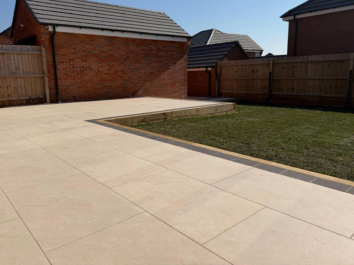Cream porcelain patio with charcoal pencil edge paving and sleepers.