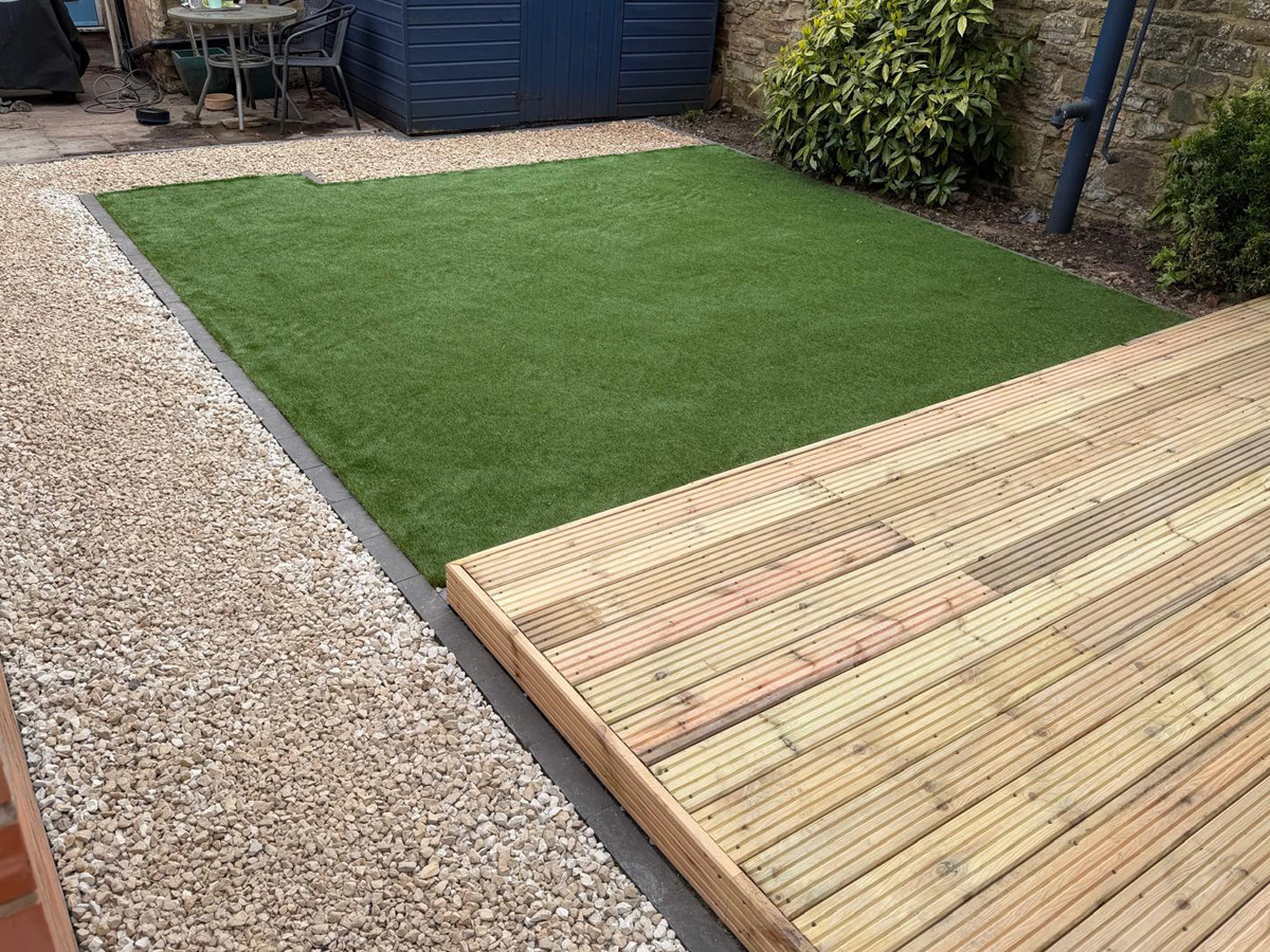 White gravel with charcoal pencil edge paving, decking and artificial turf.