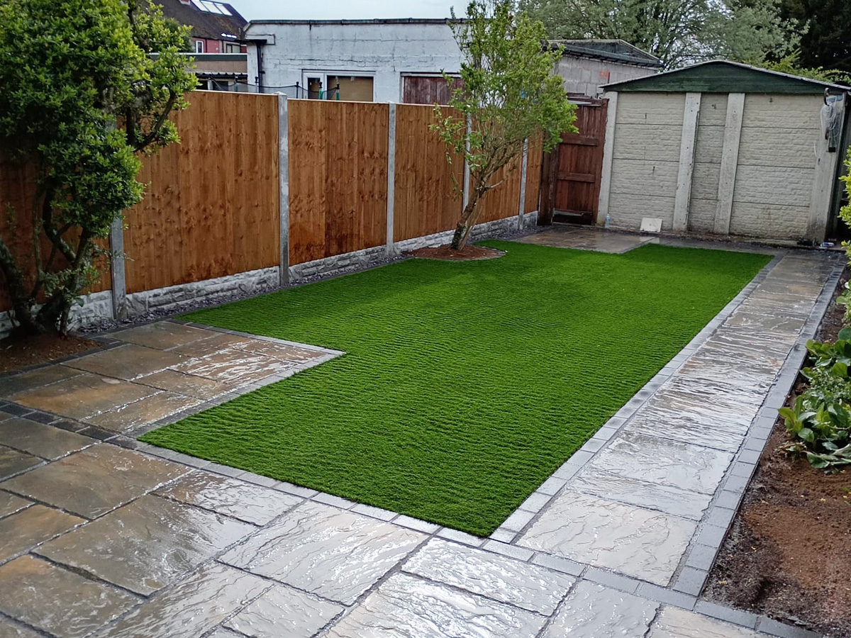 Mixed-size autumn gold patio edged with charcoal blocks and artificial turf.