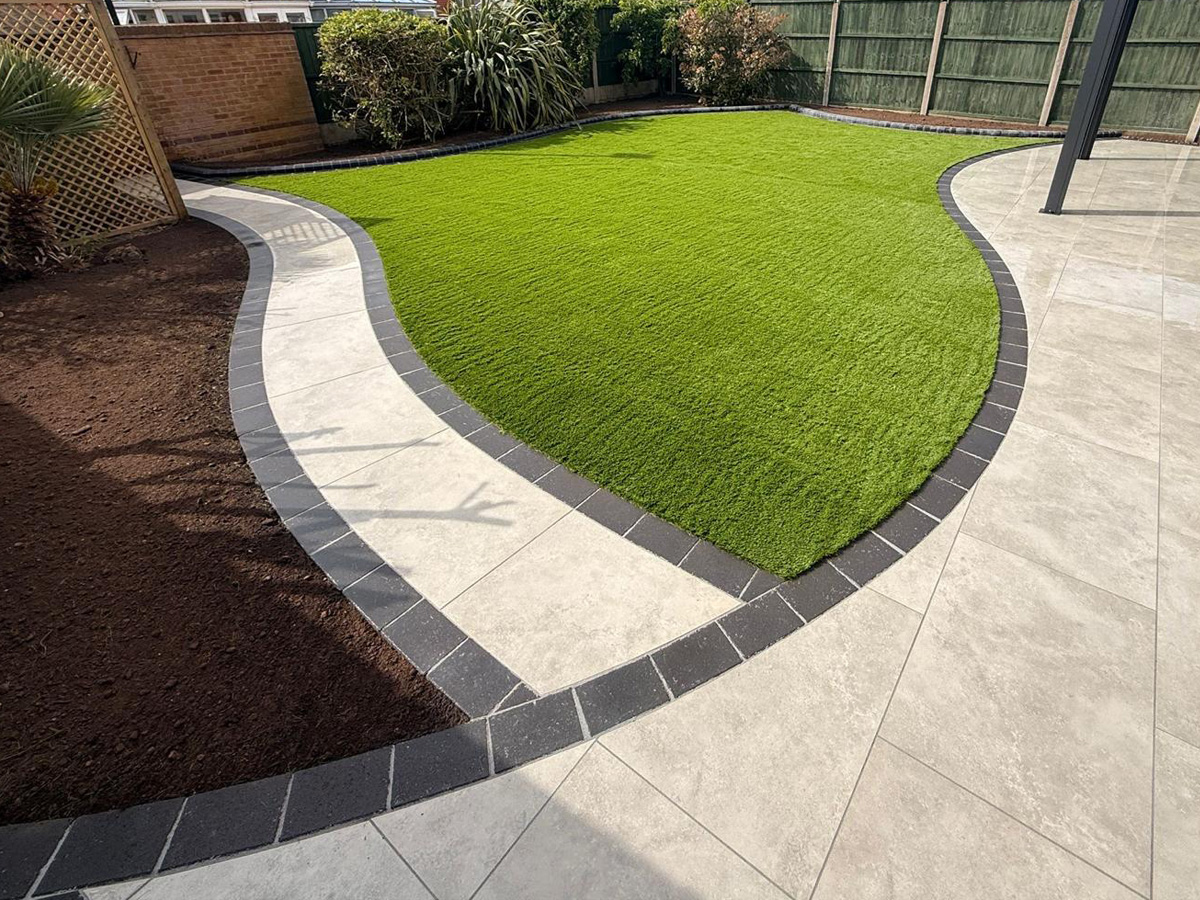 Porcelain patio and path with pencil edge paving, pergola and artificial turf.