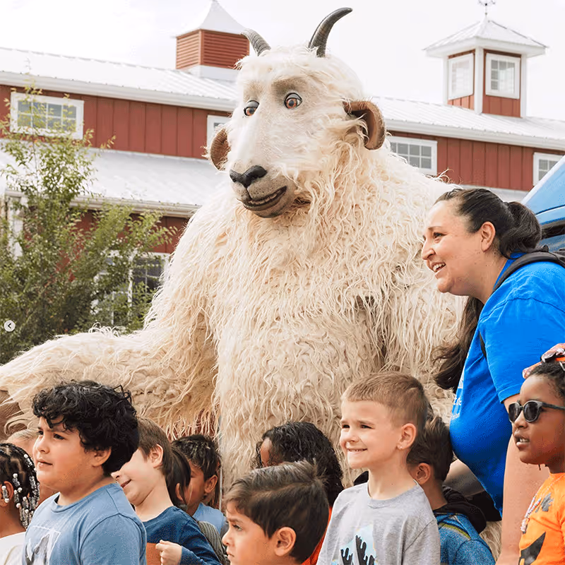Wilder stands behind smiling children and a woman outdoors near a red barn posing for a picture.