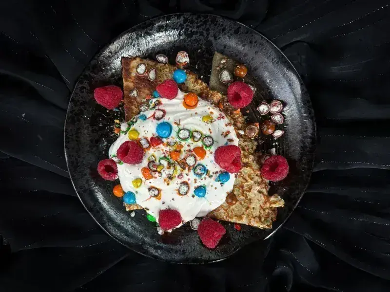 Photo d’une crêpe au skyr, framboises et M&Ms, dont une portion contient 28 g de protéines.