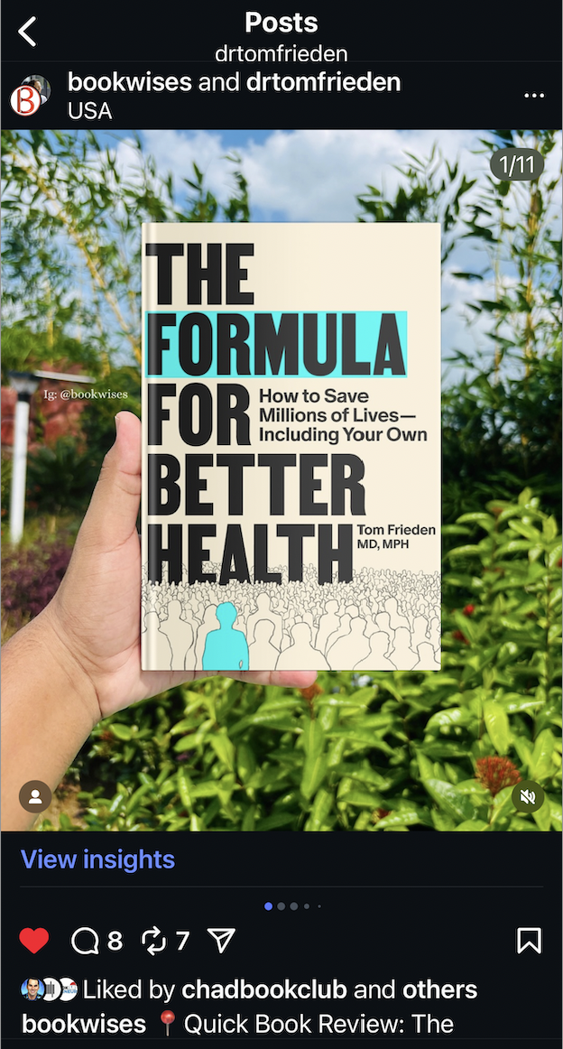Hand holding the book 'The Formula for Better Health' by Tom Frieden, against a background of green plants and blue sky.