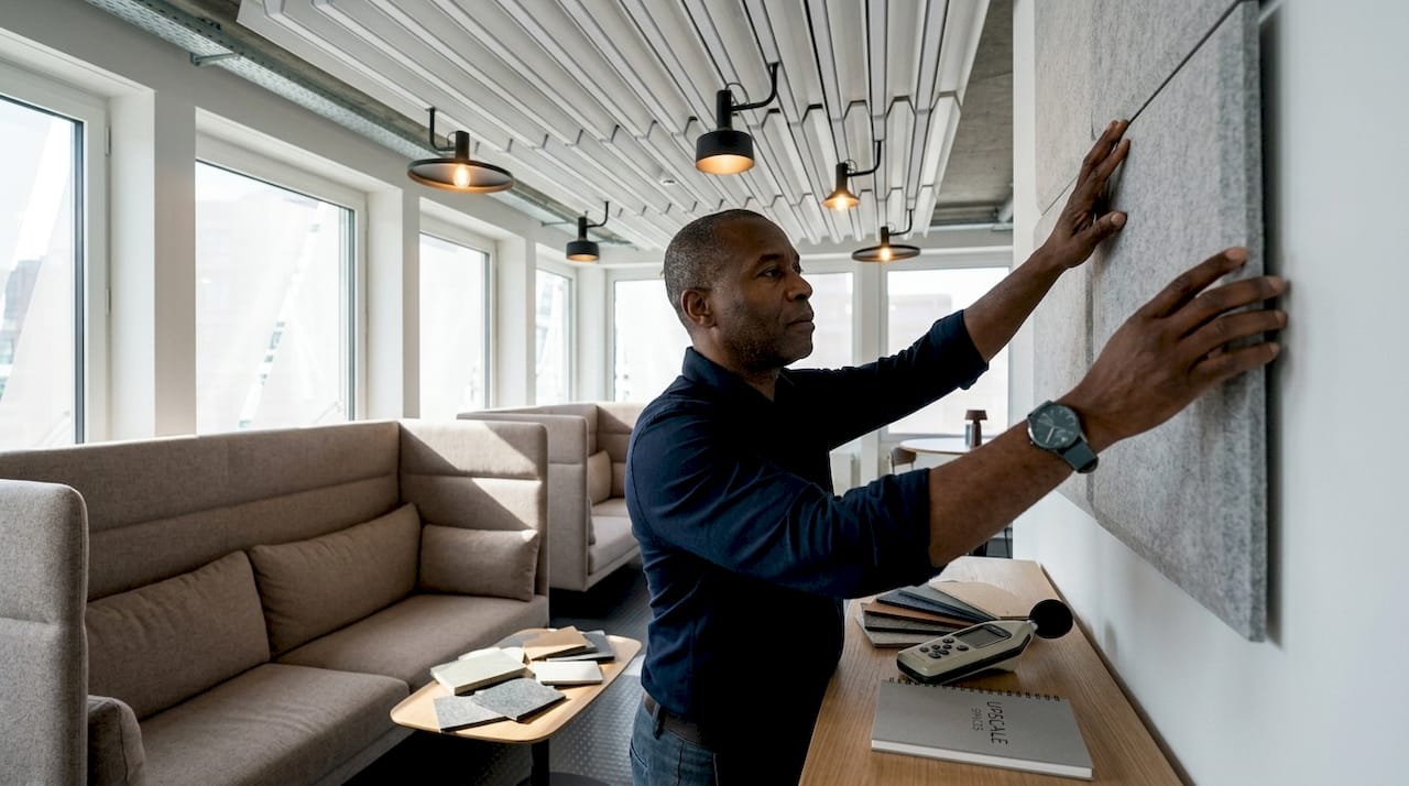 Man installing acoustic panels in breakout space