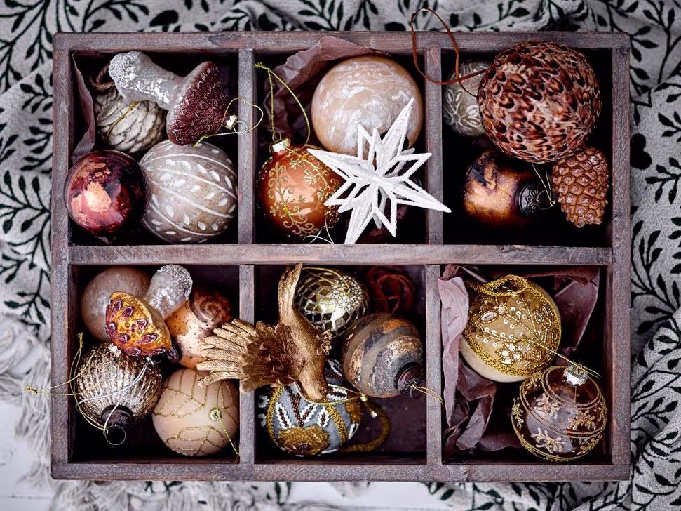 A box of assorted decorative Christmas ornaments in various textures and patterns.