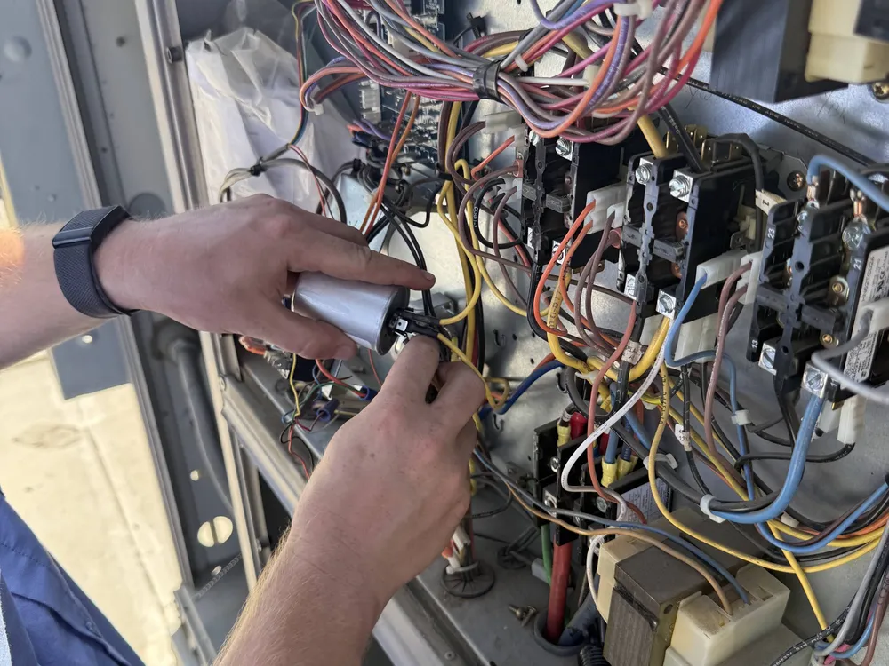 Technician replacing a capacitor in an air conditioner control panel