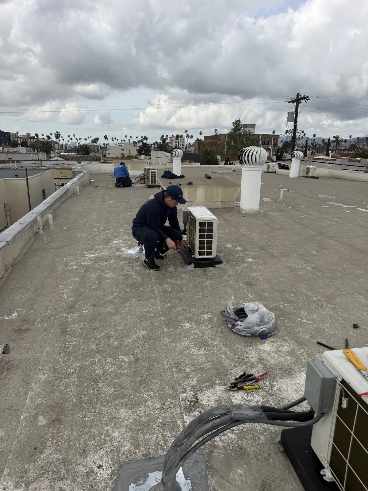 Technician working beside a rooftop outdoor unit and refrigerant line set