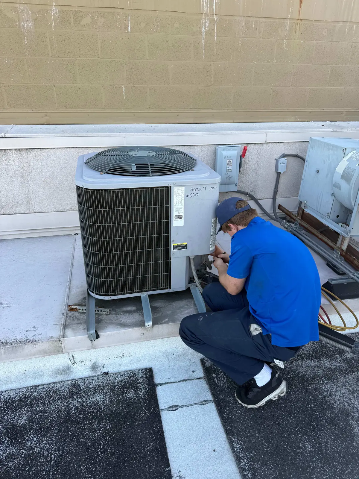 Technician installing a heat pump condenser at a Woodland Hills home