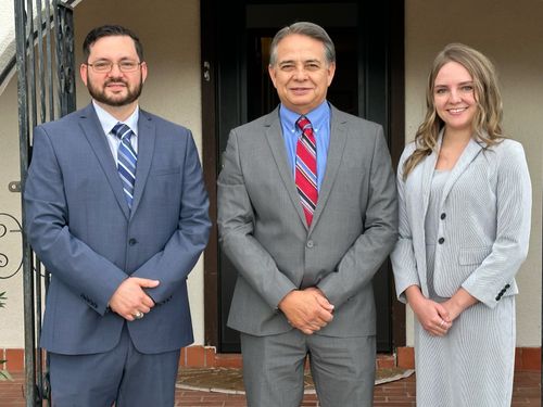 Photo of Albert, Adrian, and Christiana Valadez posing in front of their office building