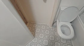 Newly installed white toilet on a recently tiled patterned floor